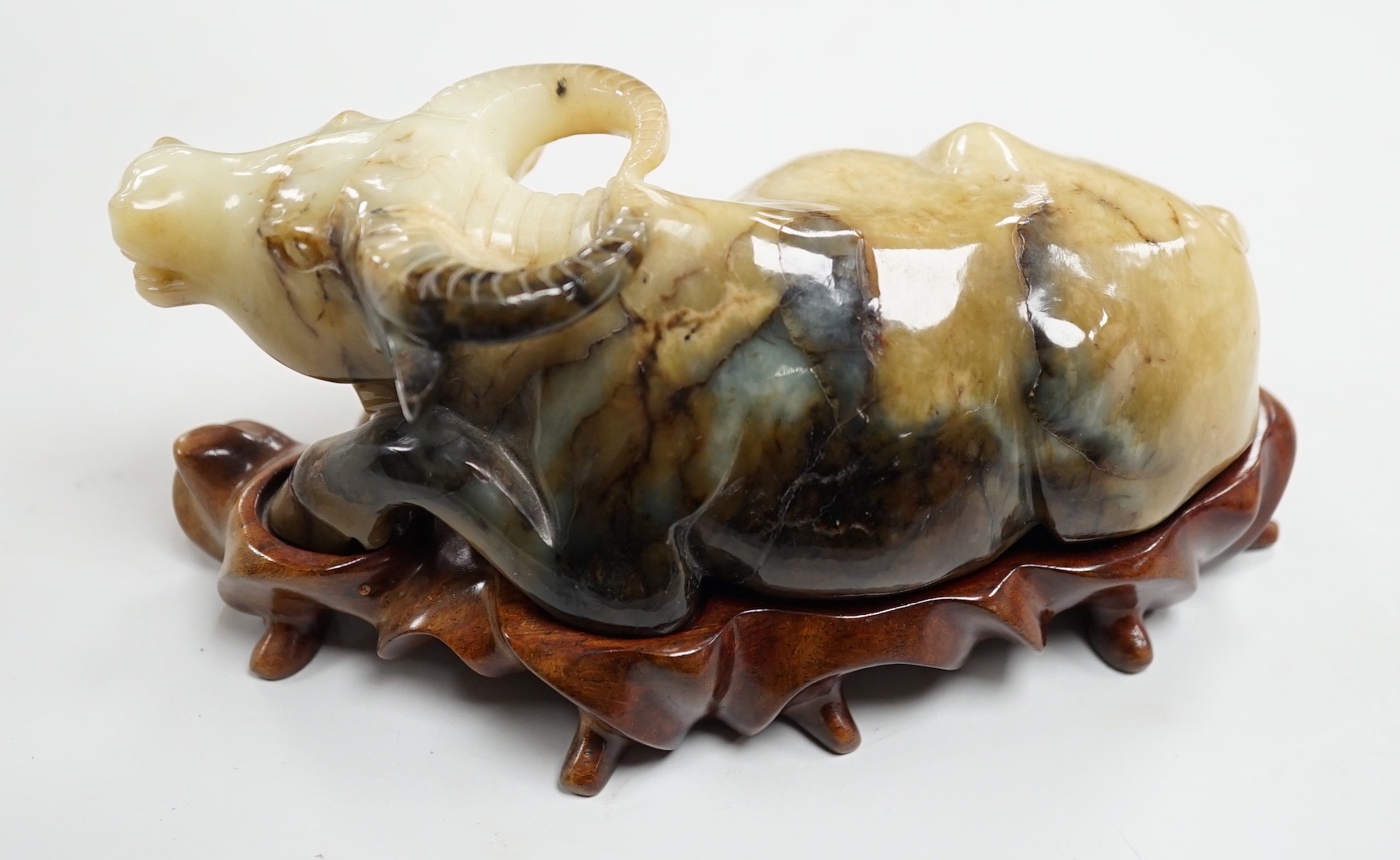 A large Chinese grey and black jade figure of a recumbent buffalo, 17cm long, wood stand